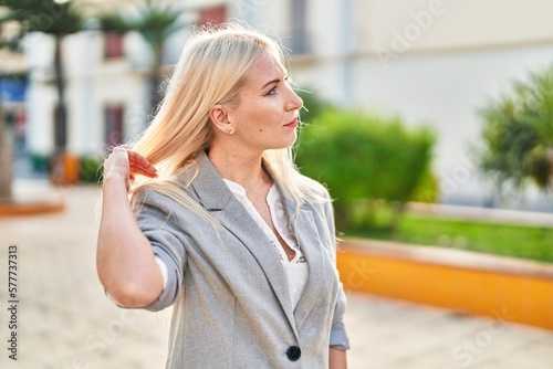 Young blonde woman standing with relaxed expression at park