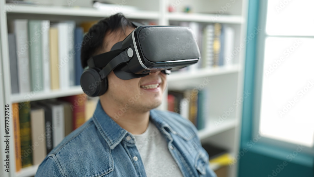 Young chinese man student smiling confident using virtual reality glasses at library university