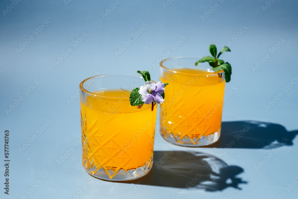 Fototapeta premium orange cocktail with mint and orange chips on a blue background