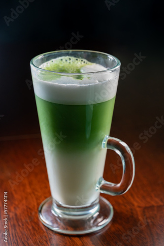 Glass of green Matcha tea made from finely ground powder of specially grown and processed green tea leaves consumed in East Asia with whipped milk
