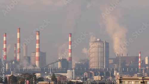 Zoom out from Large Industrial Plant and Smokestacks by Residential Town