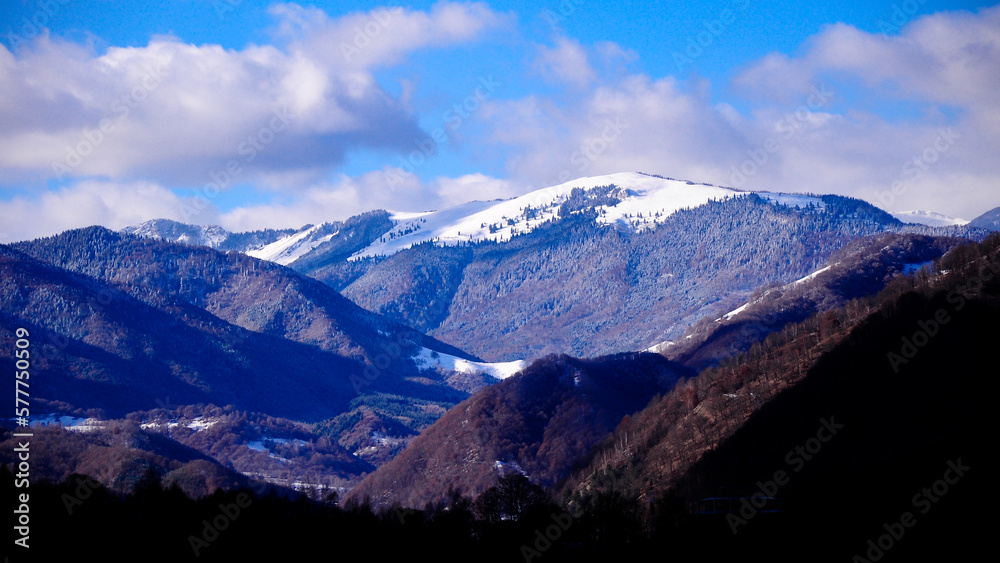 Snow in Lotru mountains. The peaks and the beech forests are covered with a layer of white snow. Shade covers the rest of the mountainsides. Carpathia, Romania. Snow in Lotru mountains. The peaks and the beech forests are covered with a layer of white snow. Shade covers the rest of the mountainsides. Carpathia, Romania.