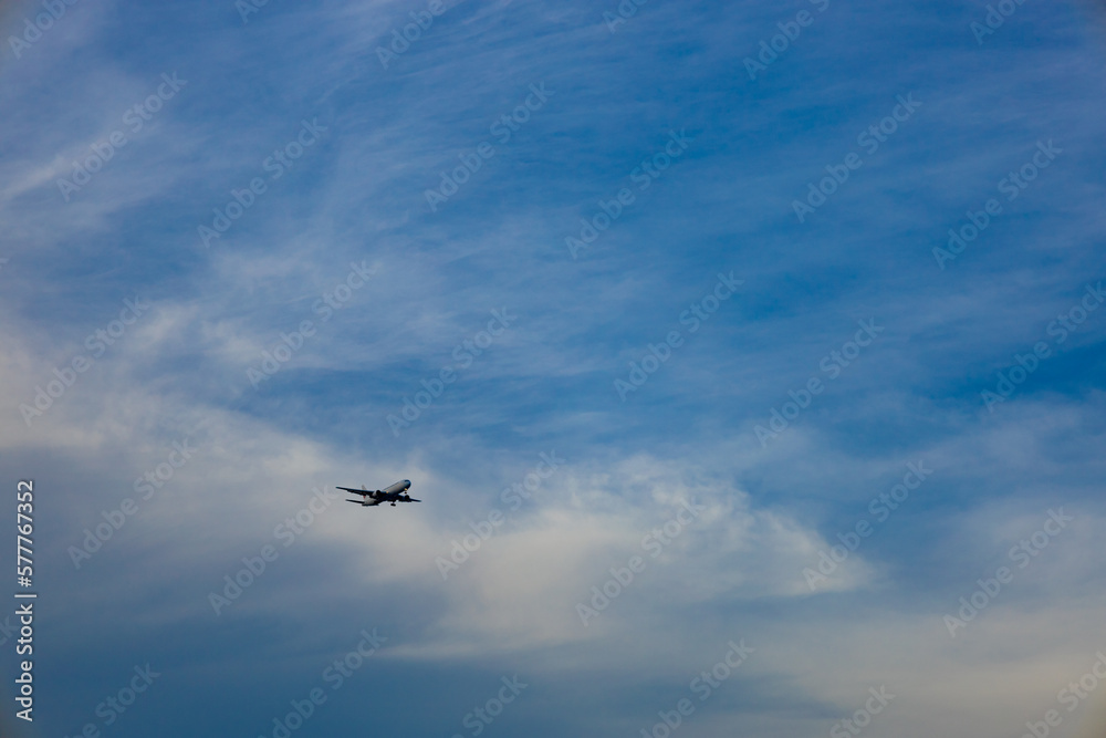 都会の空に広く大きく雄大に広がる青空と雲と、発着する夕方近くの飛行機（東京都大田区）
