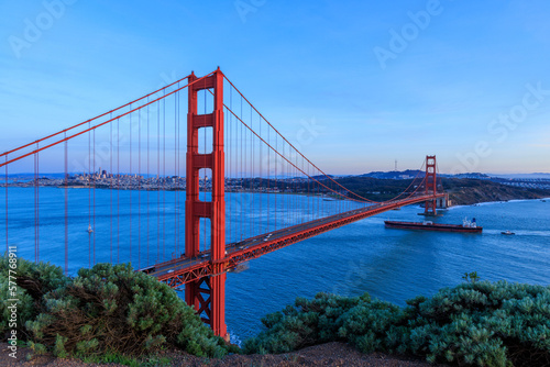 Cargo ship sails into San Francisco Bay under Golden Gate Bridge at sunset