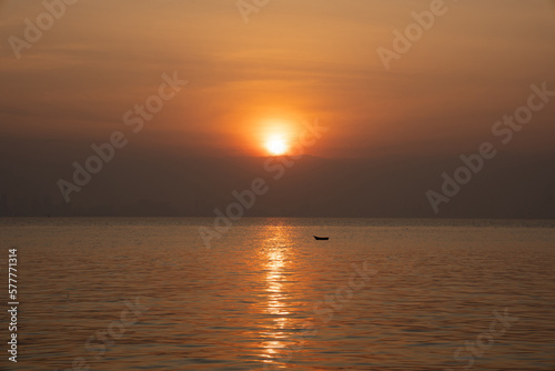 Calm sea with sunset and boat in the distance. Meditation on the background of the ocean. Calm seascape, city skyline in the distance, Thailand © asokova