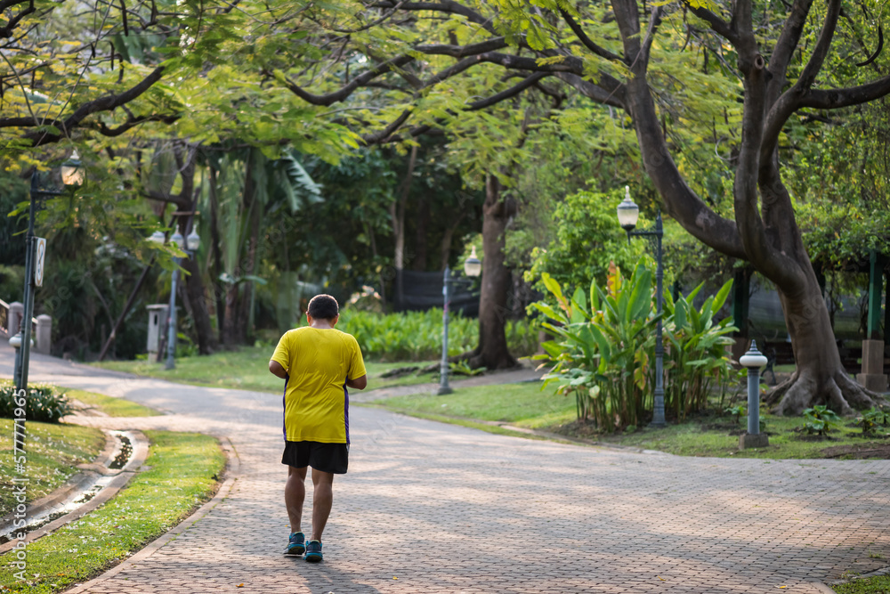 Fototapeta premium Senior old man running or jogging in park at sunrise