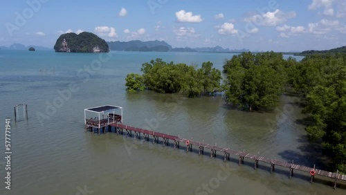 Backward reveal aerial footage of a pier and mangrove trees on sunny day and high tide. Thalane, Krabi Province, Thailand. photo