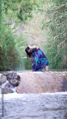 latina woman standing in a river pool wearing a dress enjoying the water and getting her hair wet in the Elqui Valley photo