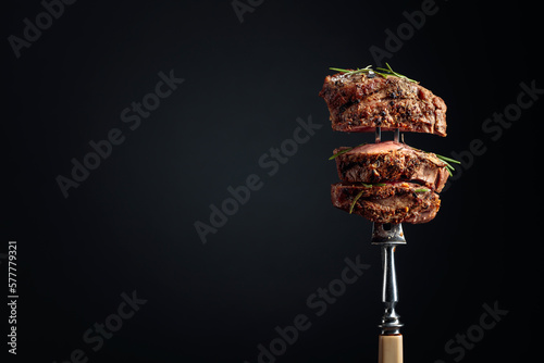 Print op canvas Medium rare beef steak with rosemary on a black background.