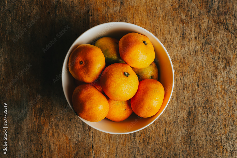 Photograph of white bowl with tangerines on a wooden background. Food concept Photograph of white bowl with tangerines on a wooden background. Food concept