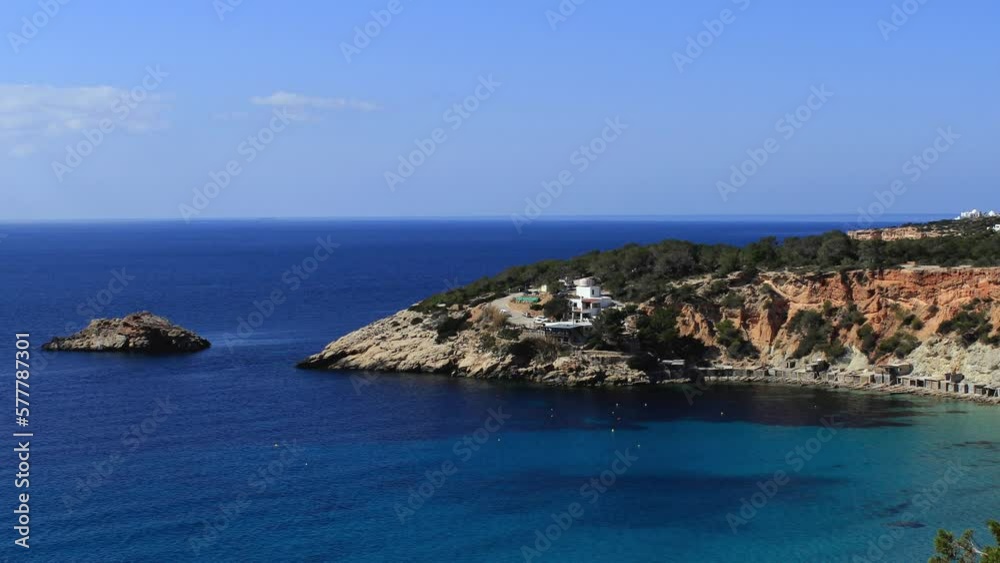 The iconic Cala Hort in the Balearic archipelago. Aerial view of the golden sand beach and the promontory which flows into a paradisiacal sea. The iconic Cala Hort in the Balearic archipelago. Aerial view of the golden sand beach and the promontory which flows into a paradisiacal sea.