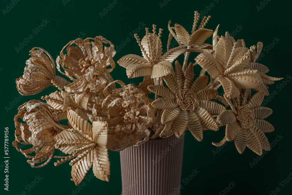 The flowers is made of straw on a green background in a cardboard vase The flowers is made of straw on a green background in a cardboard vase