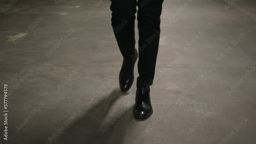 Close-up male legs walking on concrete parking businessman wearing black leather shoes and formal suit going to work cropped view unrecognizable man moving walk in underground garage business concept