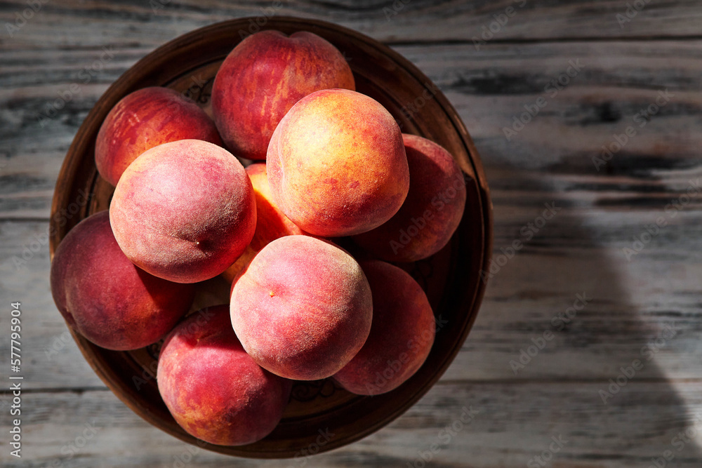 Red-yellow peaches on a clay plate on a rustic wooden table close-up, top view, copy space. View from above Red-yellow peaches on a clay plate on a rustic wooden table close-up, top view, copy space. View from above