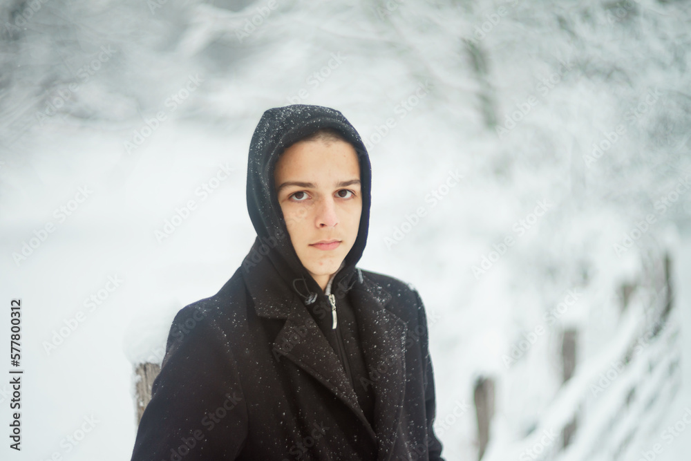 handsome young man is standing on a road covered with snow handsome young man is standing on a road covered with snow