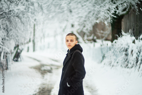 handsome young man is standing on a road covered with snow