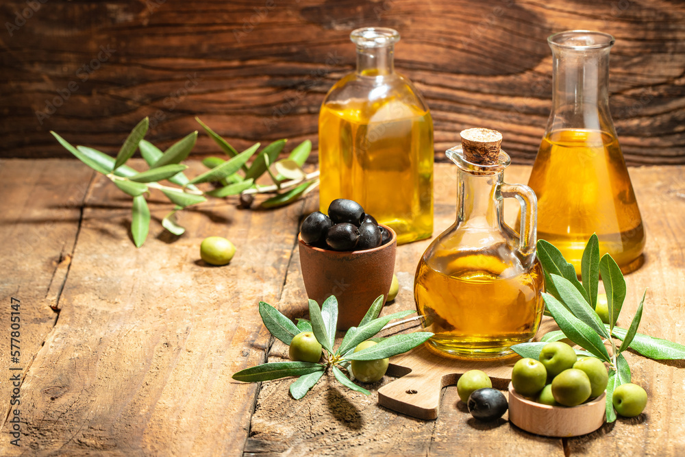 Olive oil in bottles with black and green olives and leaves. extra virgin olive oil jars on a wooden background. place for text Olive oil in bottles with black and green olives and leaves. extra virgin olive oil jars on a wooden background. place for text