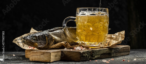 Photography Foam beer in a mug, dried fish stockfish dark background