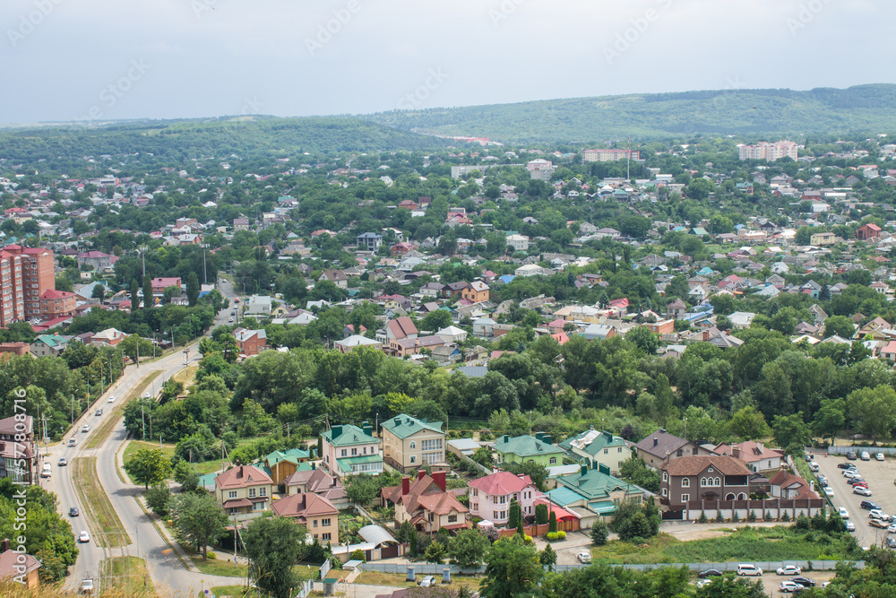 Panoramic top view of the city of Pyatigorsk in the Stavropol territory with residential buildings among green trees and cloudy sky in a haze on a summer day and space for copying