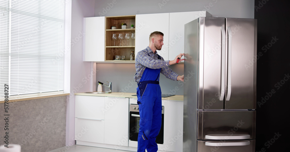 Male Worker Repairing Refrigerator With Screwdriver Male Worker Repairing Refrigerator With Screwdriver