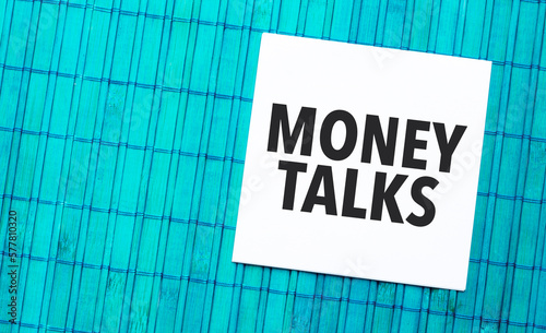 money talks word on torn paper with blue wooden background