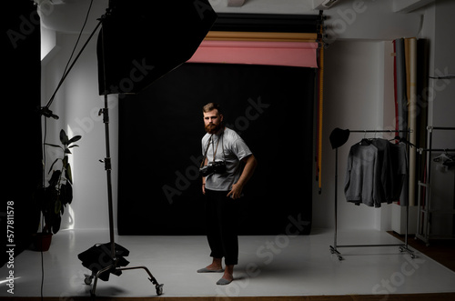 Professional handsome bearded male photographer with bunch of vintage photo cameras in photo studio.