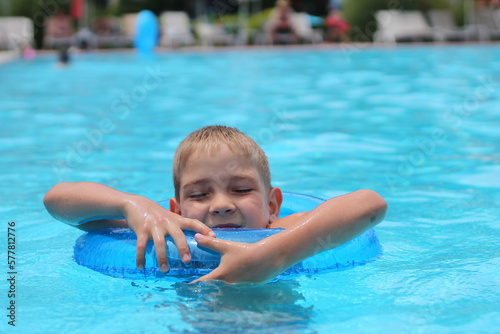 Funny little boy swims in a pool in an blue life preserver © Оксана Олейник