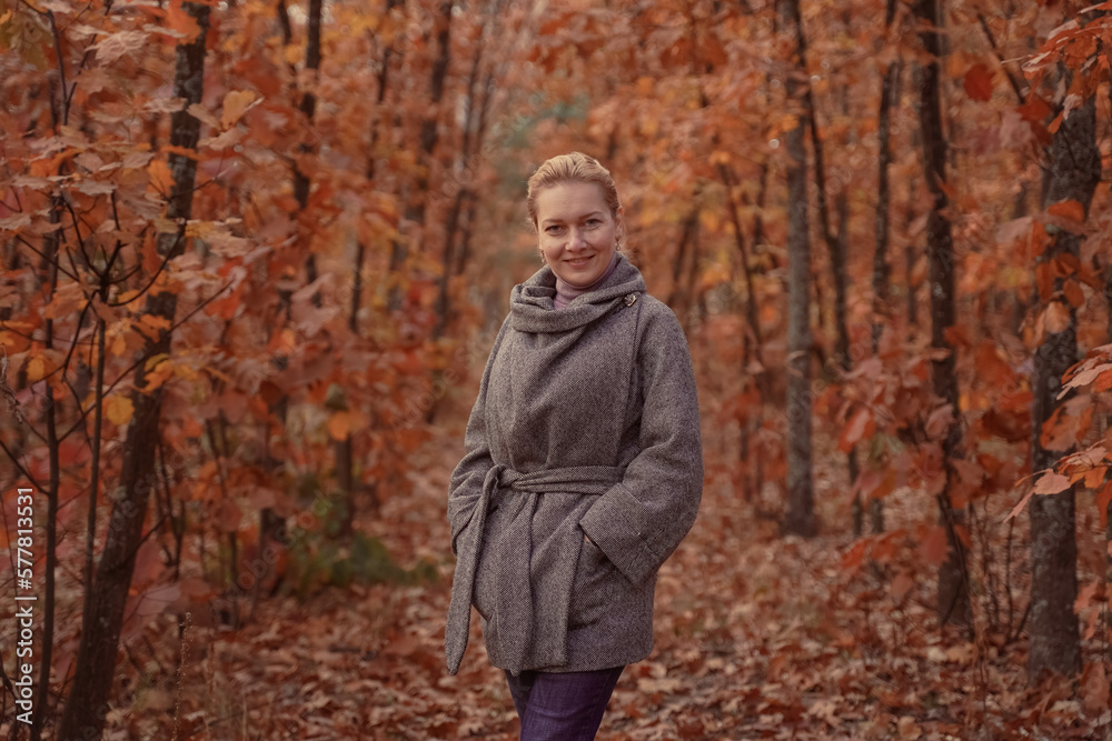 Beautiful smiling woman walking outdoors in autumn forest. Brown toned.