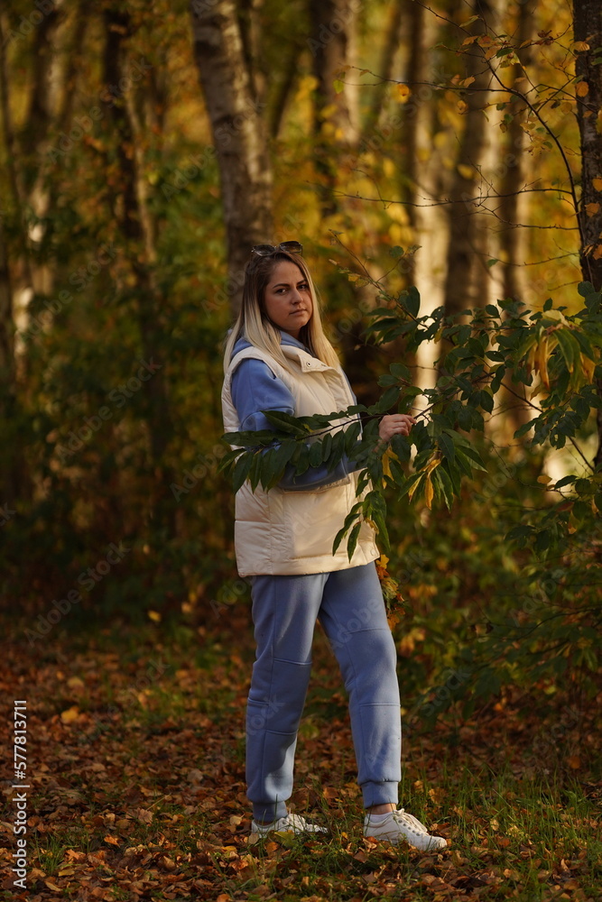 Beautiful young woman enjoying sunny autumn day in nature, walking down the forest path covered with colorful fallen leaves and relaxing, taking a breath of fresh air Beautiful young woman enjoying sunny autumn day in nature, walking down the forest path covered with colorful fallen leaves and relaxing, taking a breath of fresh air