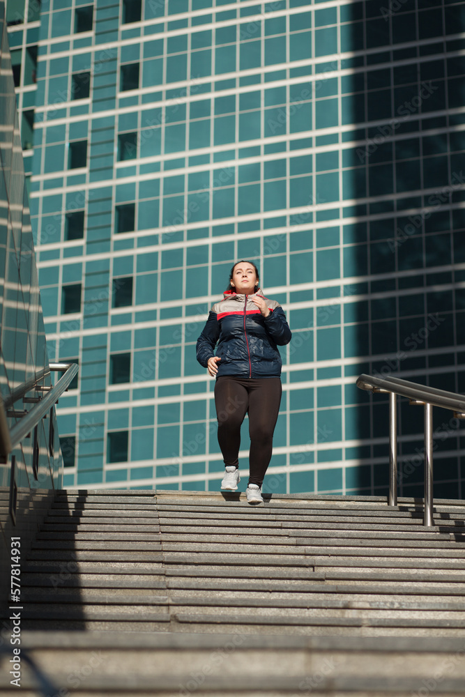 confidence overweight woman running on stairs outdoor in city