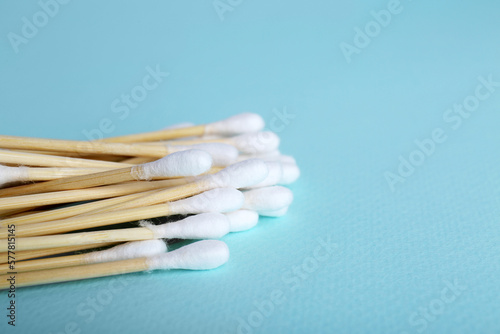 Wooden cotton buds on light blue background, closeup. Space for text