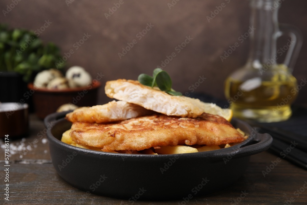 Tasty soda water battered fish and potato chips on wooden table Tasty soda water battered fish and potato chips on wooden table