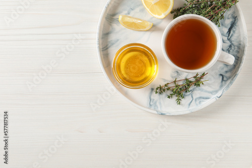 Aromatic herbal tea with thyme, honey and lemons on white wooden table, top view. Space for text