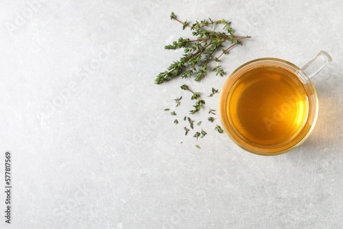 Aromatic herbal tea with thyme on light grey table, flat lay. Space for text