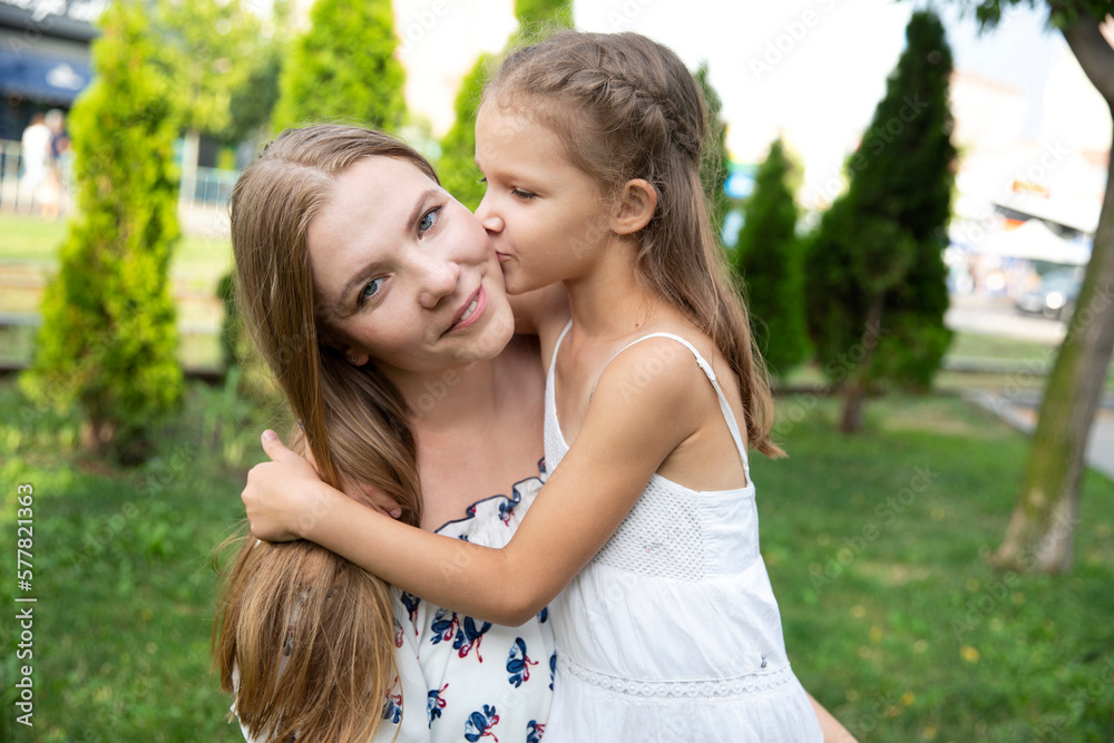 Close-up portrait of mother and child. Daughter kisses mom, happy family. Motherhood. Close-up portrait of mother and child. Daughter kisses mom, happy family. Motherhood.
