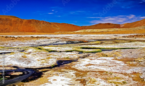 Beautiful colorful volcanic geothermal valley landscape, orange color mountains, streams blue water, white salt and yellow sulfur floes - El Tatio geysers field, Atacama desert, Chile