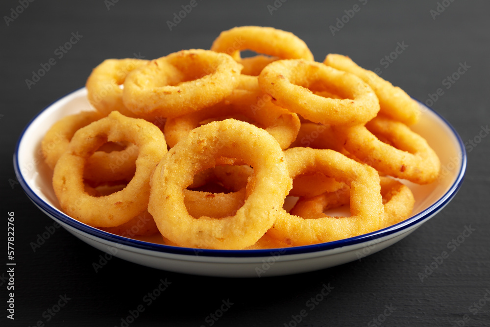 Homemade Breaded Onion Rings on a Plate on a black surface, side view. Close-up. Homemade Breaded Onion Rings on a Plate on a black surface, side view. Close-up.