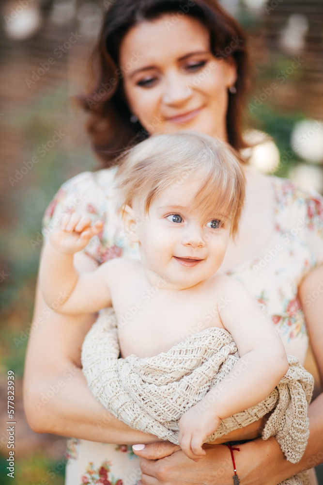 Obraz premium A young woman holds her little son in her arms in the garden at sunset