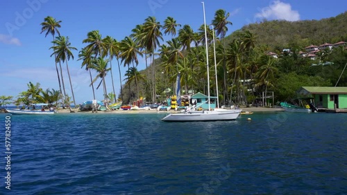 Marigot Bay, Saint Lucia. Idyllic bay and hurricane hole on the western coast of the Caribbean island country of St Lucia. Surrounded on three sides by steep, forested hills. Sand spit with palm trees photo