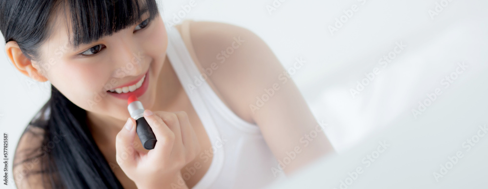Fototapeta premium Beauty of young asian woman with learning makeup with lipstick on mouth watching laptop computer with tutorial course online on bed, female teaching and explain make up with cosmetic on streaming.