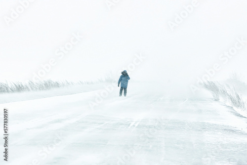 Snowstorm in the city winter is cold a teenager is walking along the road he is blown away by the wind.
