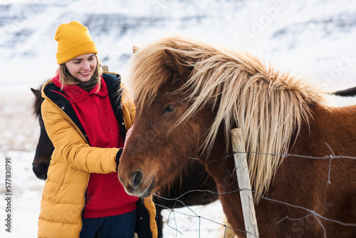 a girl takes care of a horse in winter photo