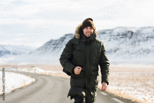 a smiling man walks along a winter road between mountains