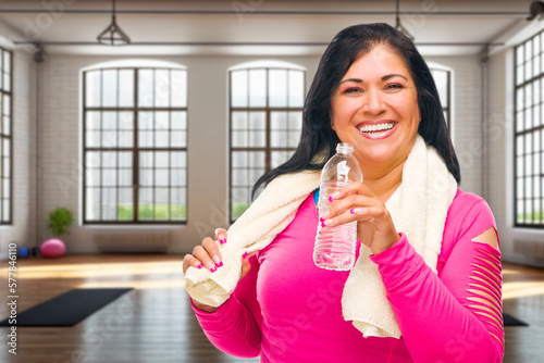 Happy Hispanic Woman with Towel and Bottle of Water Inside Yogo Studio. Some of the elements in this image are Generative AI. photo