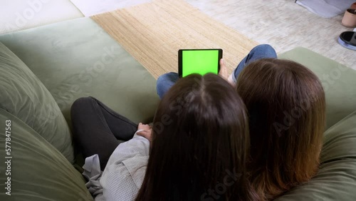 Close up of using tablet with green screen and scrolling while sitting in room. Females holding black tablet with chroma key in hand, tech concept. Video 4K.