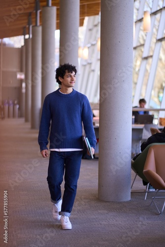 фотографія Handsome Hispanic male student, holding laptop and visiting a modern library campus