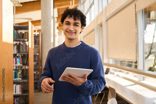 фотографія Handsome Hispanic male student with tablet, smiling, at camera, visiting a moder