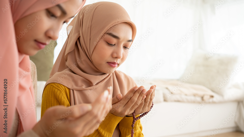 Two Muslim women in beautiful hijab dress sitting praying together. Idea for faith and trust in god. Two Muslim women in beautiful hijab dress sitting praying together. Idea for faith and trust in god.