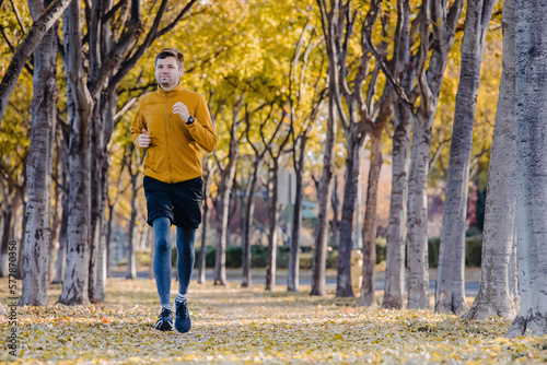 Man running on the street with lots of yellow leaves on the ground, jogging