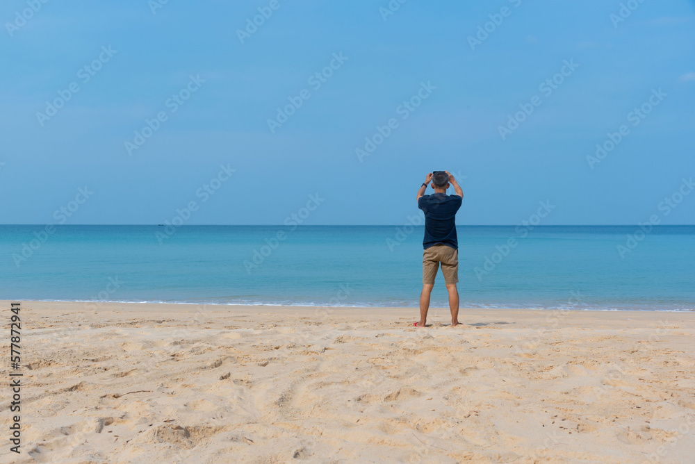 A senior adult male taking photograph on the beach.